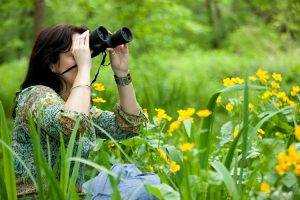 Female in a garden with binoculars - Binoculars for bird watching in the garden