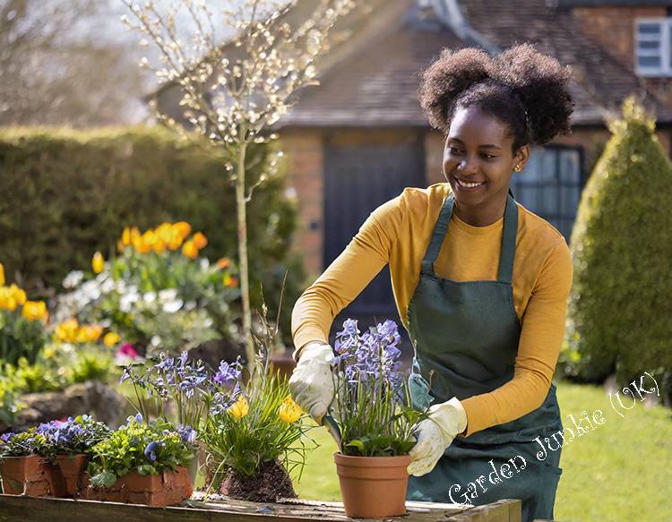 A black lady potting up plants in a garden- Gardening Month by Month – April